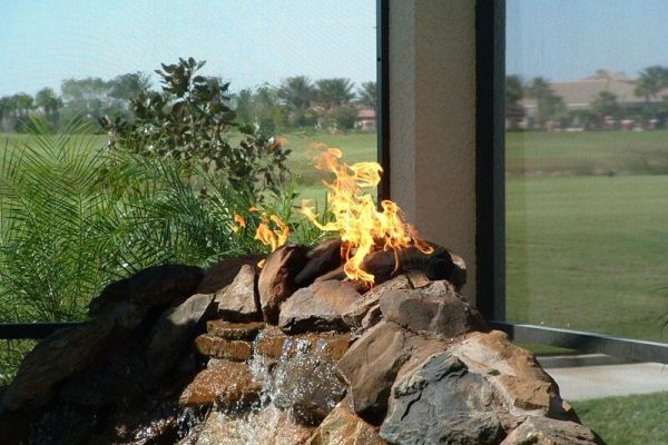 propane fire coming out of rocks with waterfall below